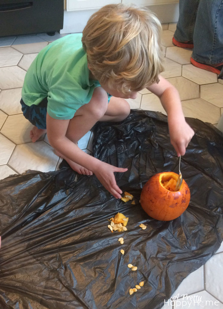 kid scooping out pumpkin guts