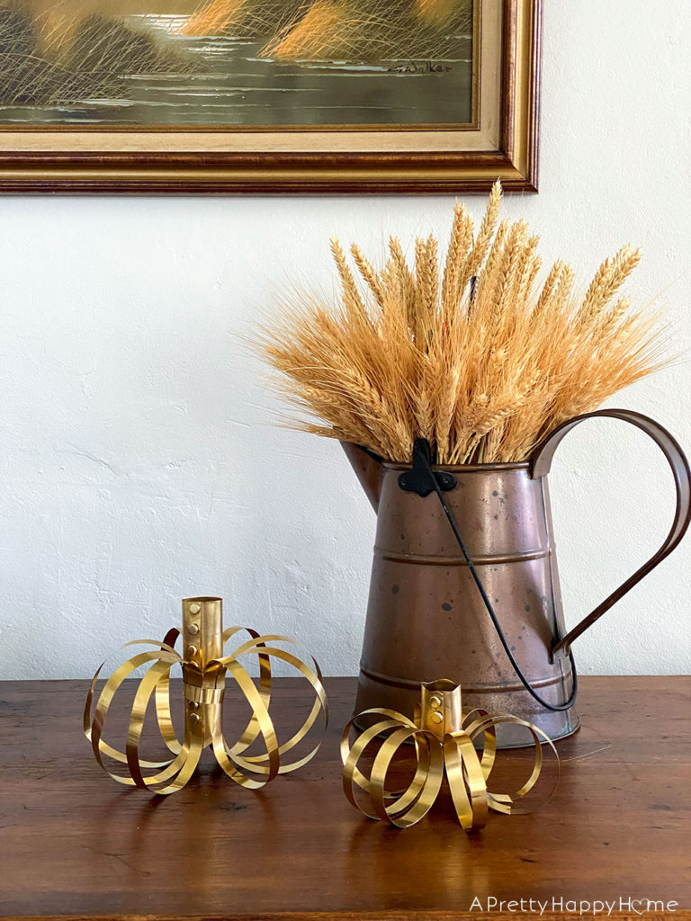 5 Fall Decorating Tricks To Give Your Home Cozy Vibes decorate with wheat stalks and brass pumpkins