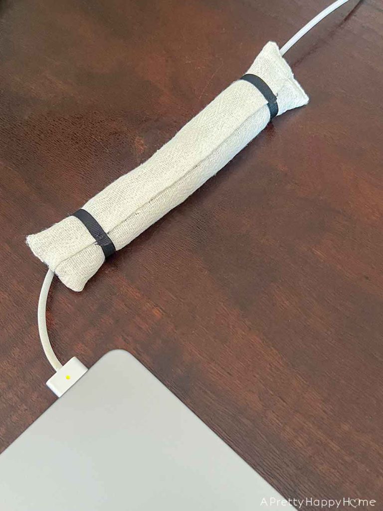 DIY weighted cord holder using rice and fabric to keep charging cords on a desk