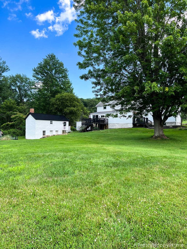 The Best Part Of Summer is being outside the back view of a colonial farmhouse and adjacent buildings with a black metal roof