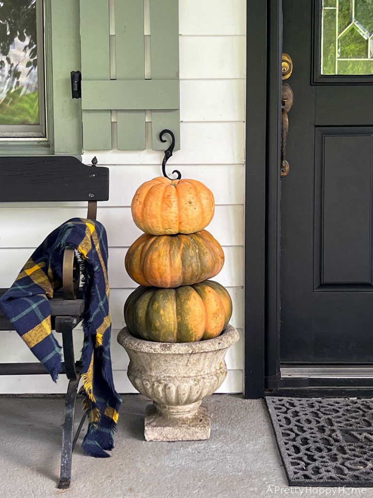Our Fall Front Porch with pumpkin topiary in a concrete planter and a black farmhouse bench
