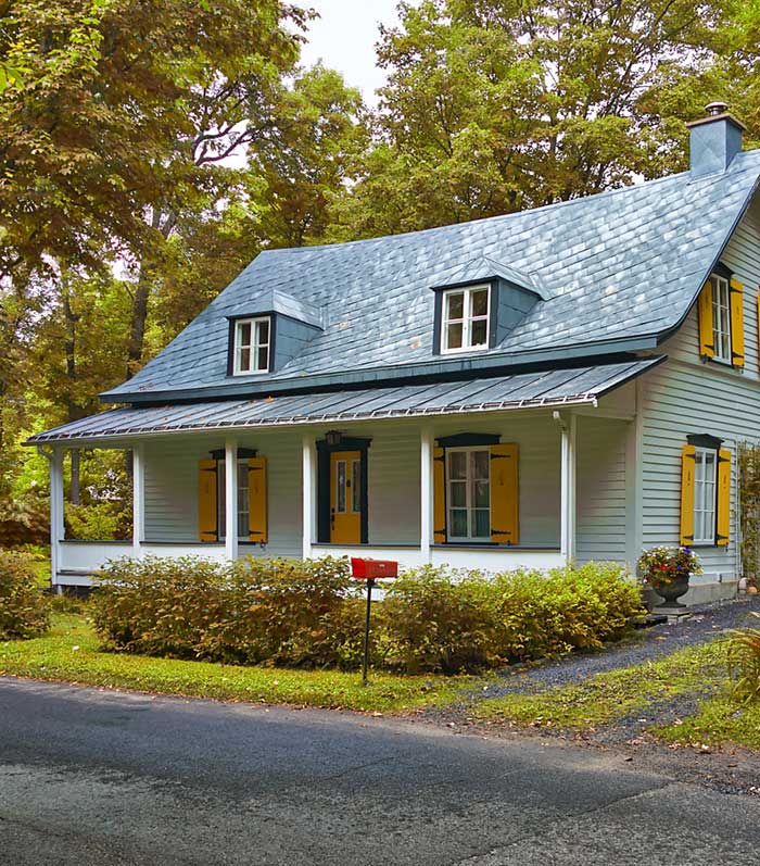 white cape cod home with yellow shutters and yellow door via town and country living on the happy list