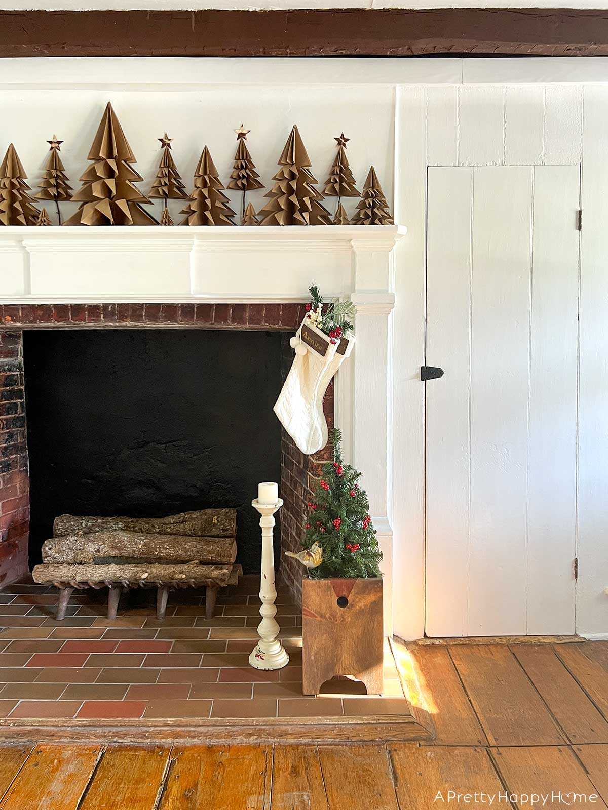 1700s farmhouse dining room with large fireplace decorated for christmas with origami trees made from brown kraft paper christmas reflections 2023