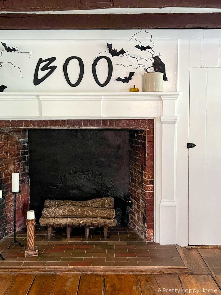 boo halloween mantel with hand painted boo sign, paper bats, and branches