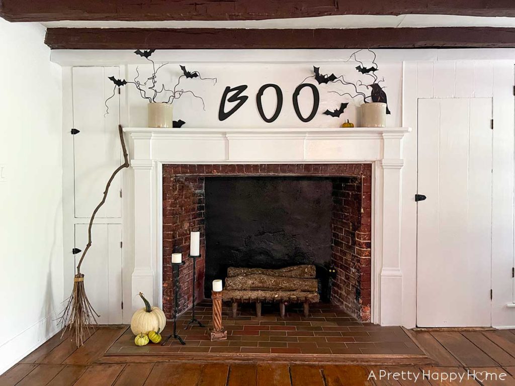 boo halloween mantel with hand painted boo sign, paper bats, and branches and diy witch broom made from branches