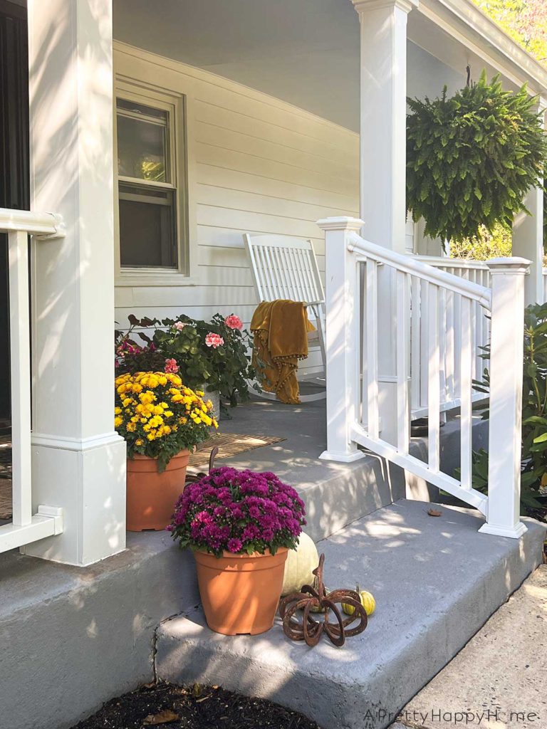 Fall front porch farmhouse porch decorated for fall with paint blue ceiling natural rug and fall flowers