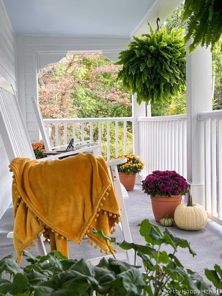 Fall front porch farmhouse porch decorated for fall with paint blue ceiling natural rug and fall flowers