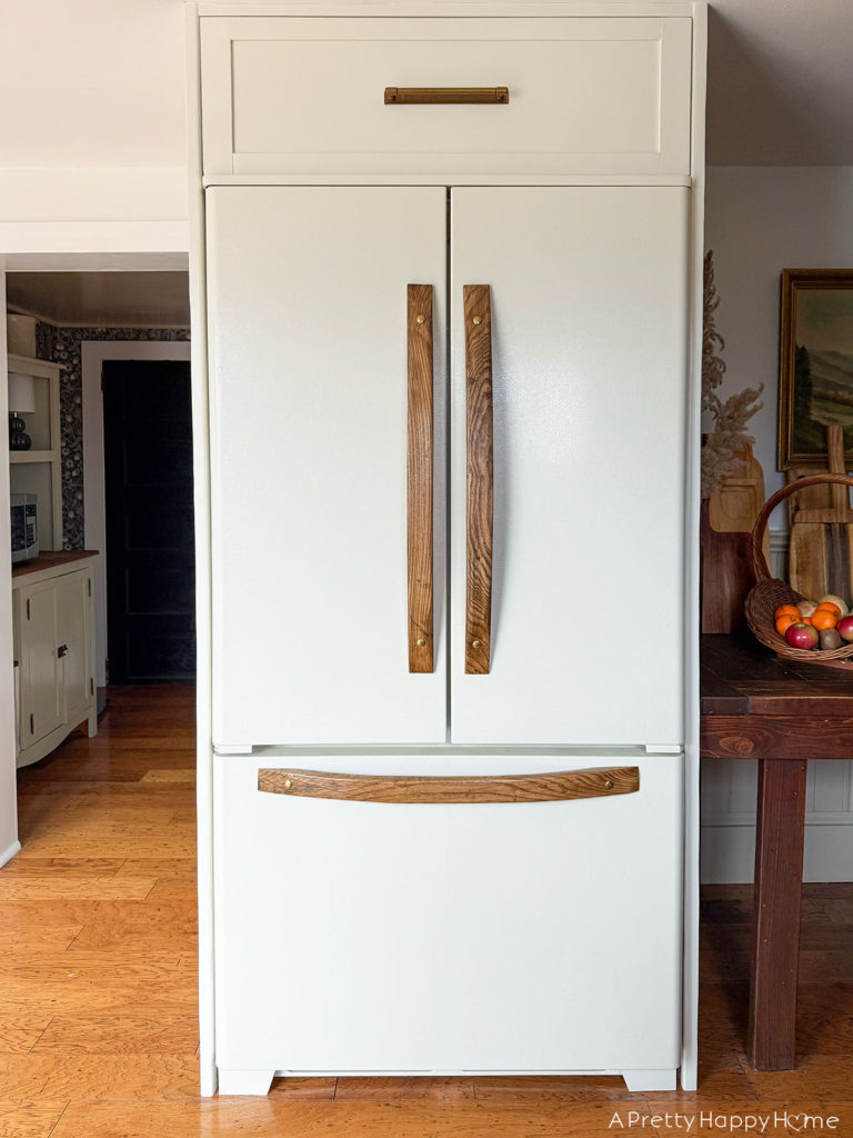 building in an old fridge to make it look custom and panel ready. refrigerator with wood handles and cabinet feet. refrigerator with slide out drawer above fridge. how to customize an old refrigerator.