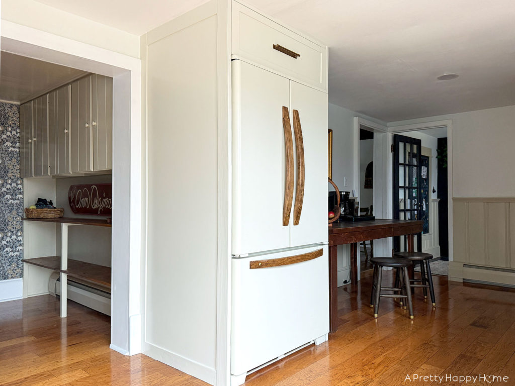 building in an old fridge to make it look custom and panel ready. refrigerator with wood handles and cabinet feet. refrigerator with slide out drawer above fridge. how to customize an old refrigerator.