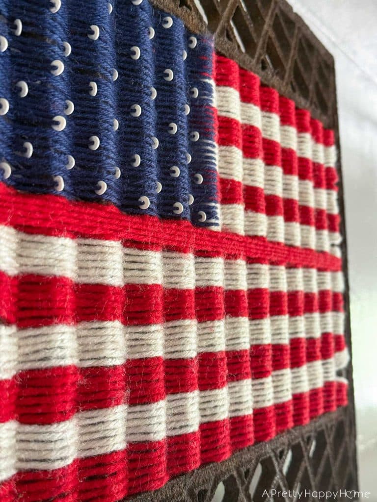 Woven American Flag on an Antique Grate in a colonial era farmhouse flag is woven with red white and blue yarn