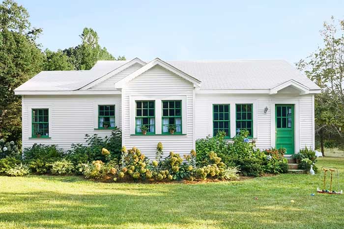 white clapboard house with green window grids via country living on the happy list photo Becky Luigart-Stayner