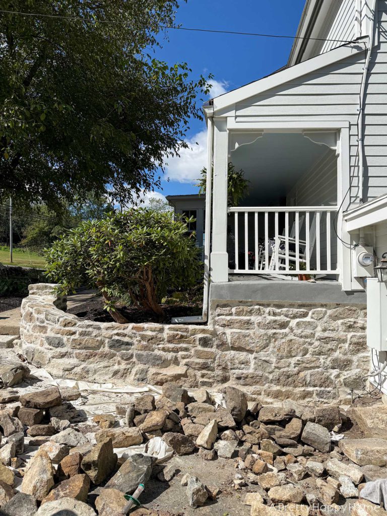 Curved Fieldstone Wall: Part 5, Porch Wall removing concrete skim coat on a stone foundation wall and repointing with lime mortar connecting a stone foundation to a stone wall
