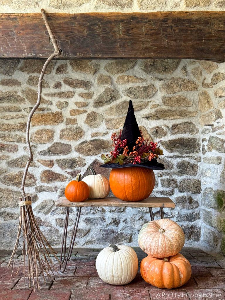 diy floral witch's hat sitting on a pumpkin in front of a stone fireplace