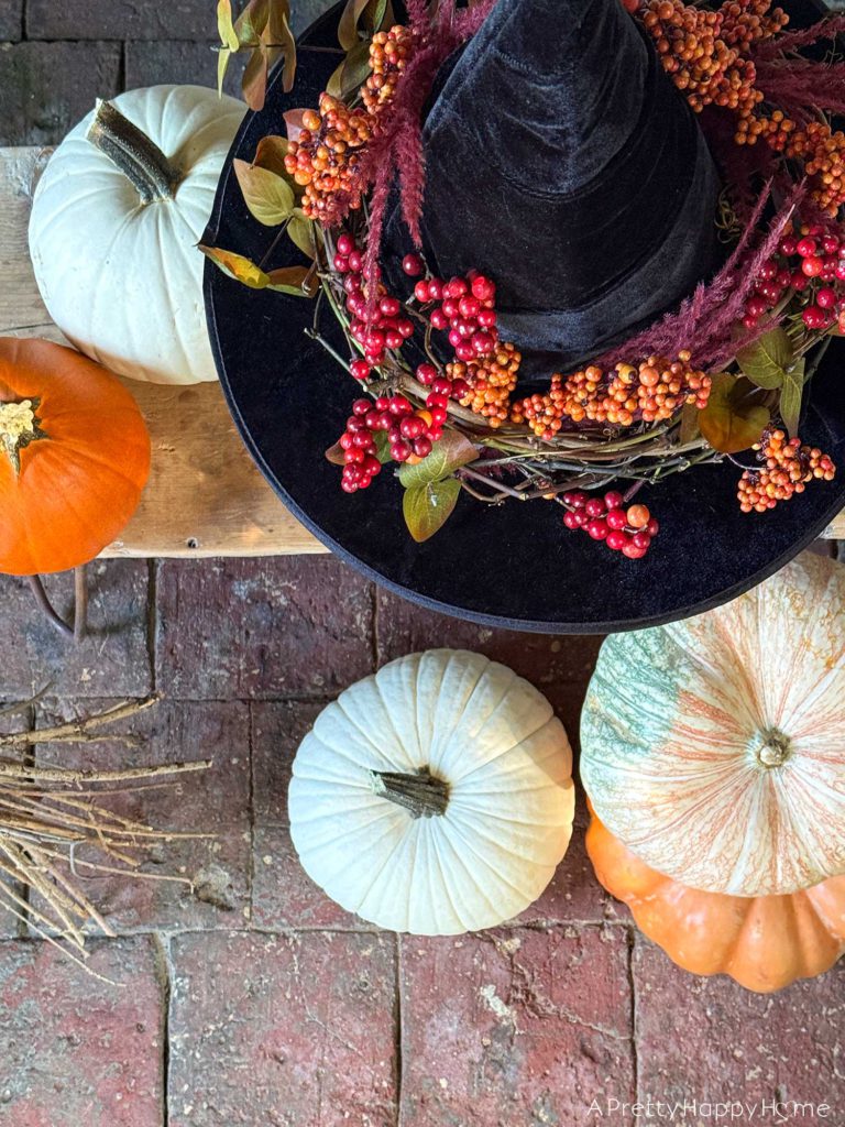 diy floral witch's hat sitting on a pumpkin in front of a stone fireplace
