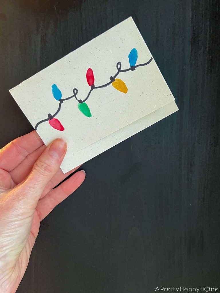 handmade card made to look like a strand of christmas lights using a black marker for the wire and red, yellow, blue, and green watercolor paint for the lights.