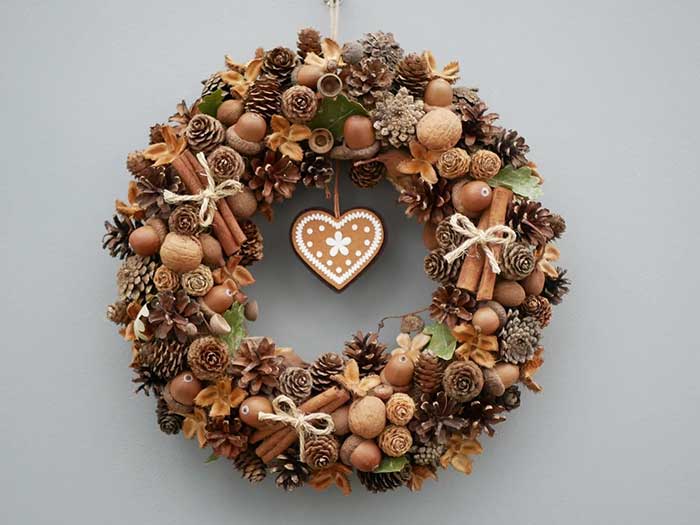winter wreath fashioned from in shell nuts like walnuts, acorns, pinecones, and cinnamon sticks. There is a gingerbread heart hanging from the center of the wreath. It comes in various sizes and is sold by etsy shop style sparkle and it featured on the blog post 5 ways to decorate with nuts for christmas